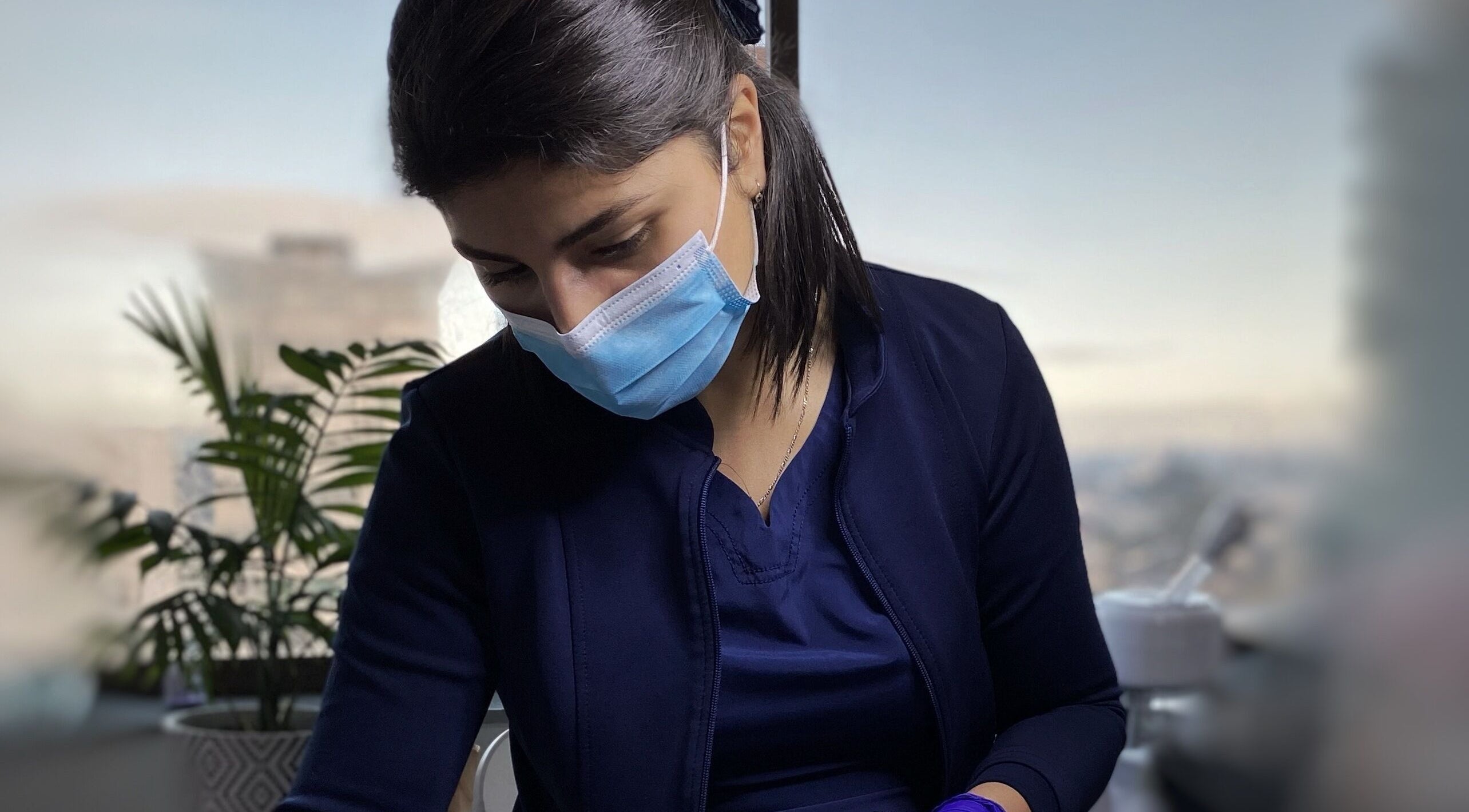 Esteticista en De Florencia, Temuco, Araucanía, CL, realiza tratamiento facial con mascarilla de seguridad.