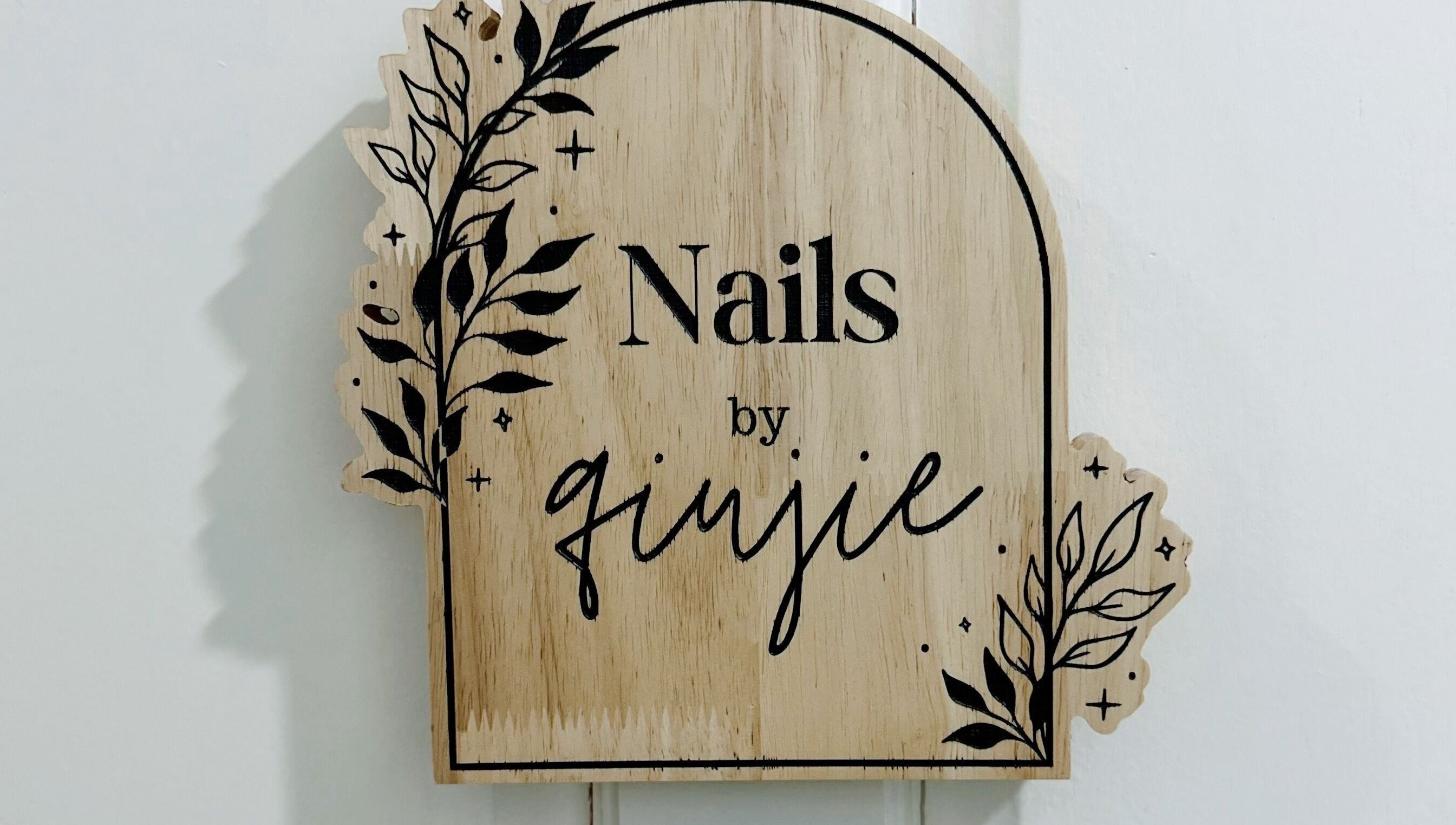 Wooden sign with 'Nails by Qj' at Bandar Seri Begawan, BN, featuring elegant leaf design.