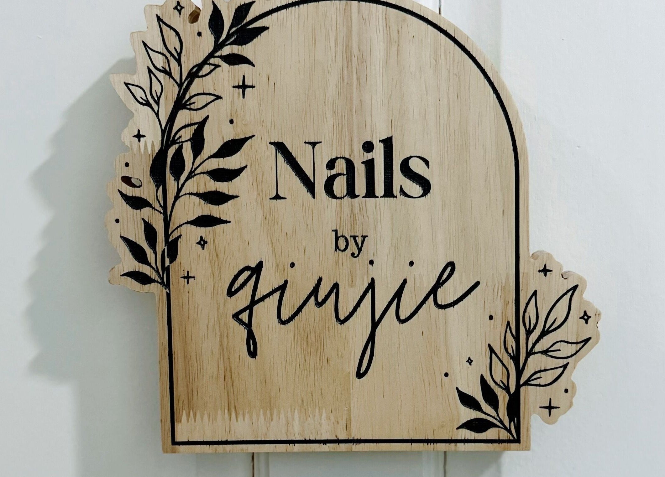 Wooden sign with 'Nails by Qj' at Bandar Seri Begawan, BN, featuring elegant leaf design.