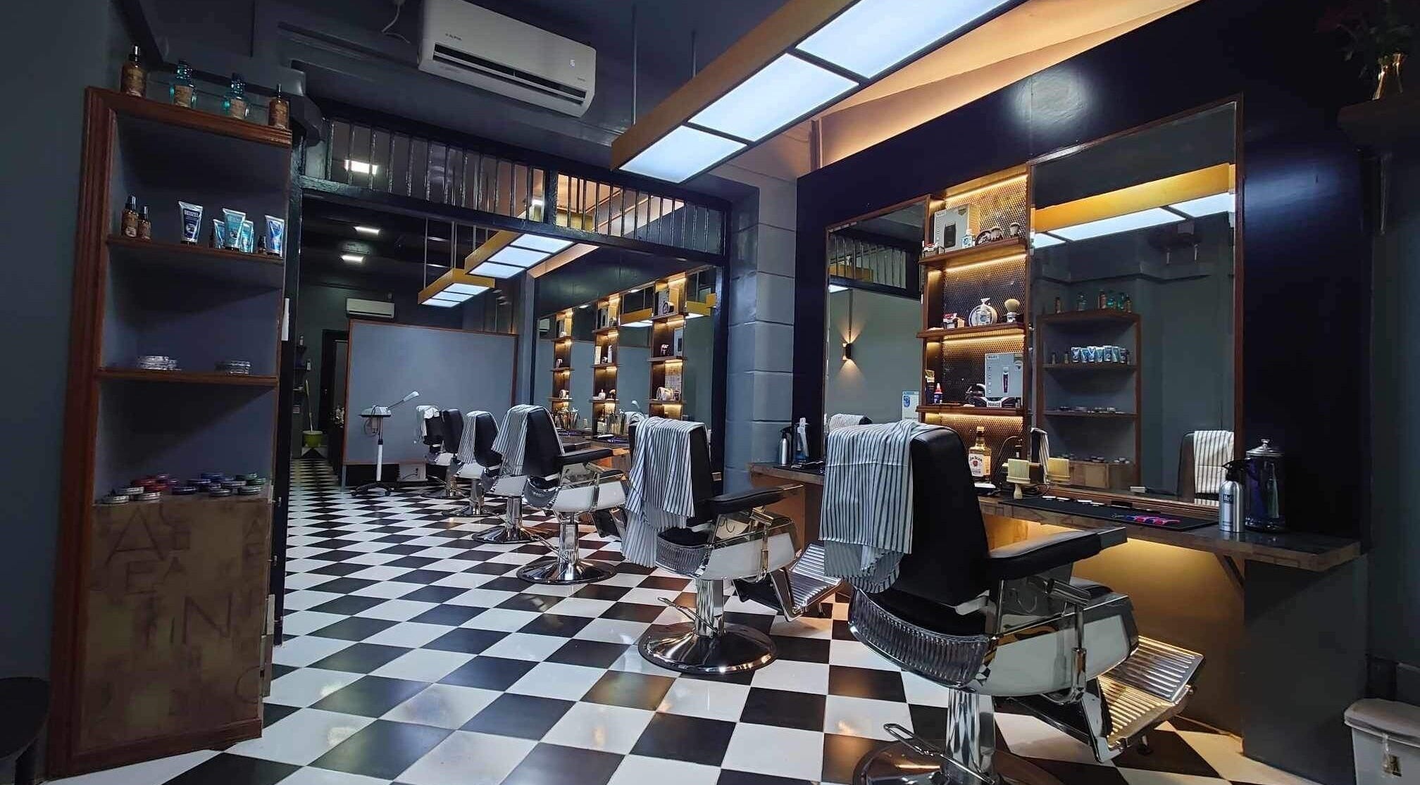Modern interior of Aliencut Barbershop in Yangon, showcasing stylish chairs and well-lit mirrors.