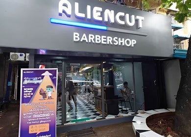 Front view of Aliencut Barbershop in Yangon, Yangon Region, MM with modern design and vibrant signage.