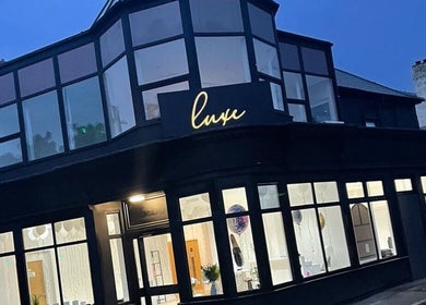 Exterior view of Renū at night in West Kirby, England, GB featuring modern glass facade.