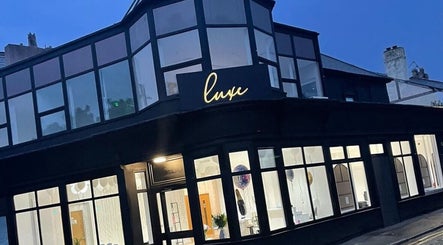 Exterior view of Renū at night in West Kirby, England, GB featuring modern glass facade.