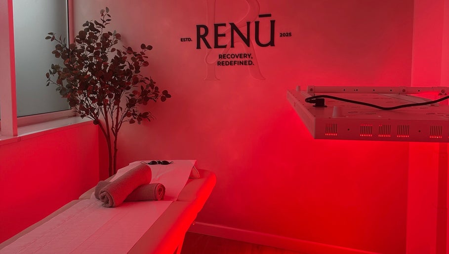 Relaxing room at RENŪ in West Kirby, England with red ambient lighting and massage table.
