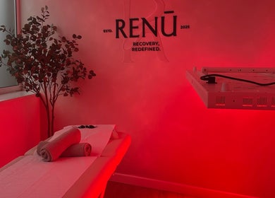 Relaxing room at RENŪ in West Kirby, England with red ambient lighting and massage table.