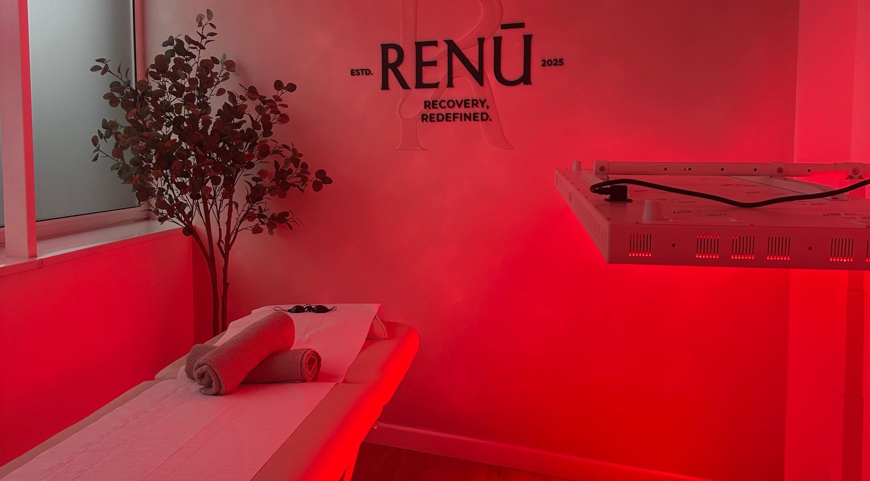 Relaxing room at RENŪ in West Kirby, England with red ambient lighting and massage table.