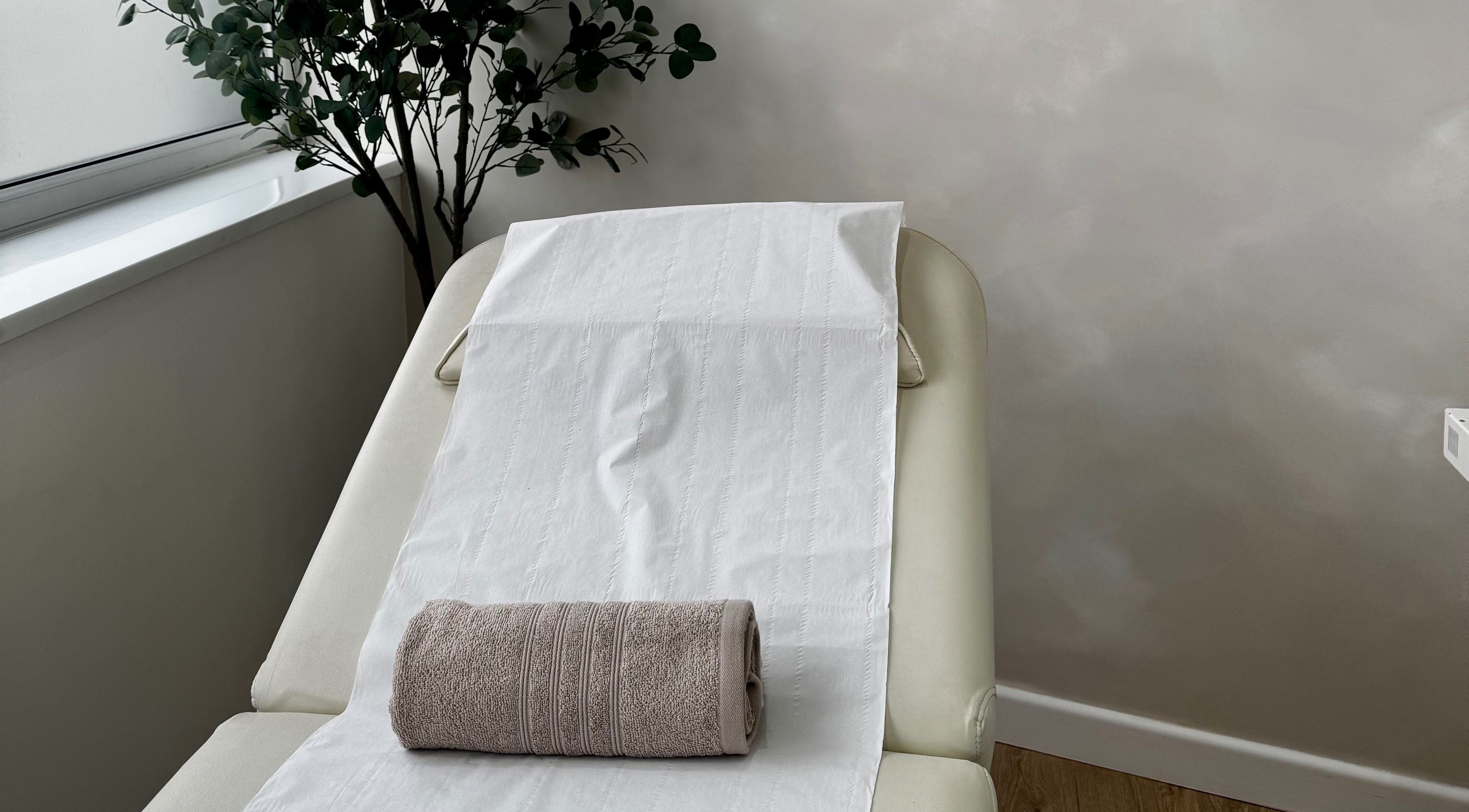 Tranquil spa bed with rolled towel at RENŪ, West Kirby, England, GB, offering a relaxing ambiance.