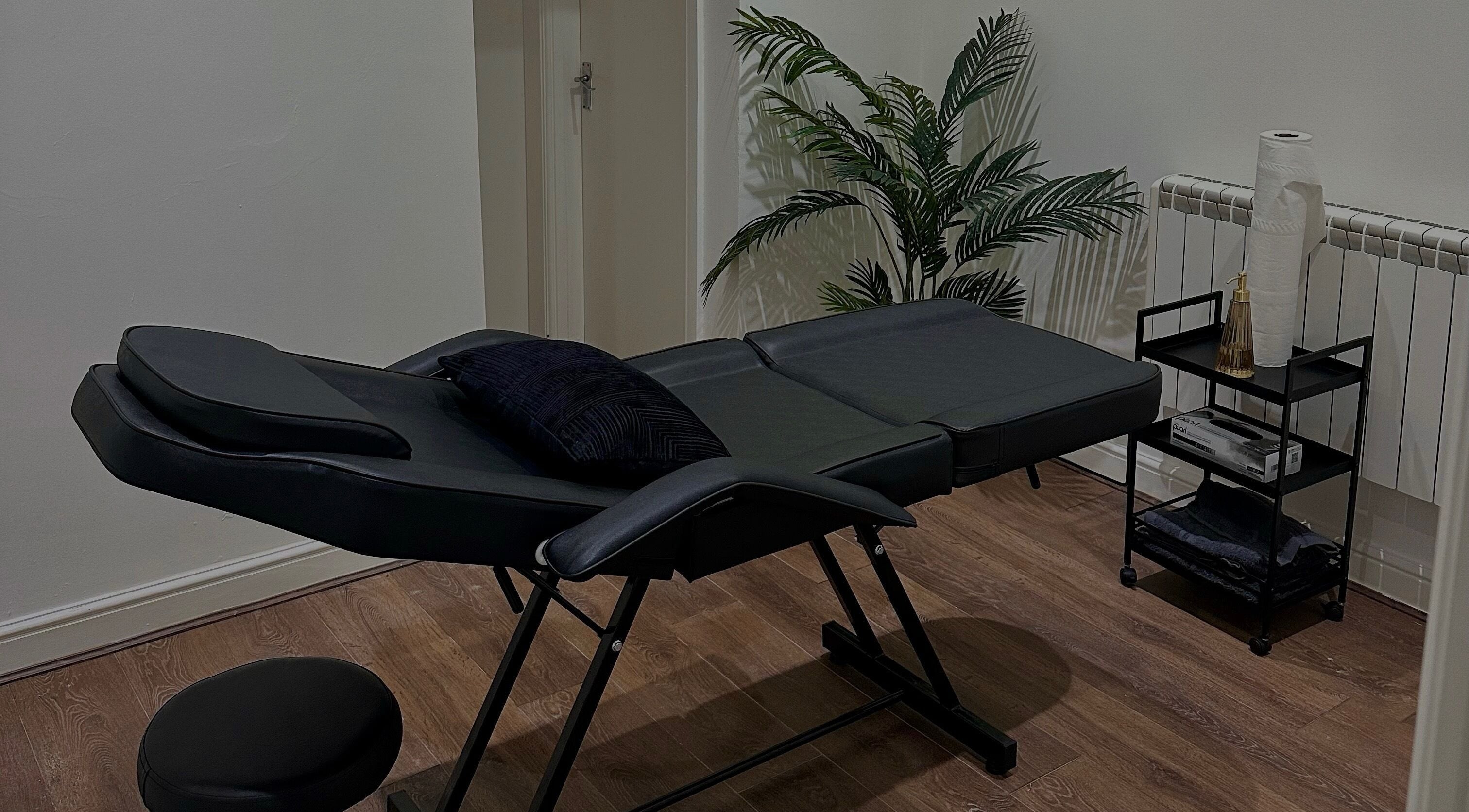A serene massage room at RENŪ (Liverpool), Liverpool, England, GB with a black massage table and calming decor.