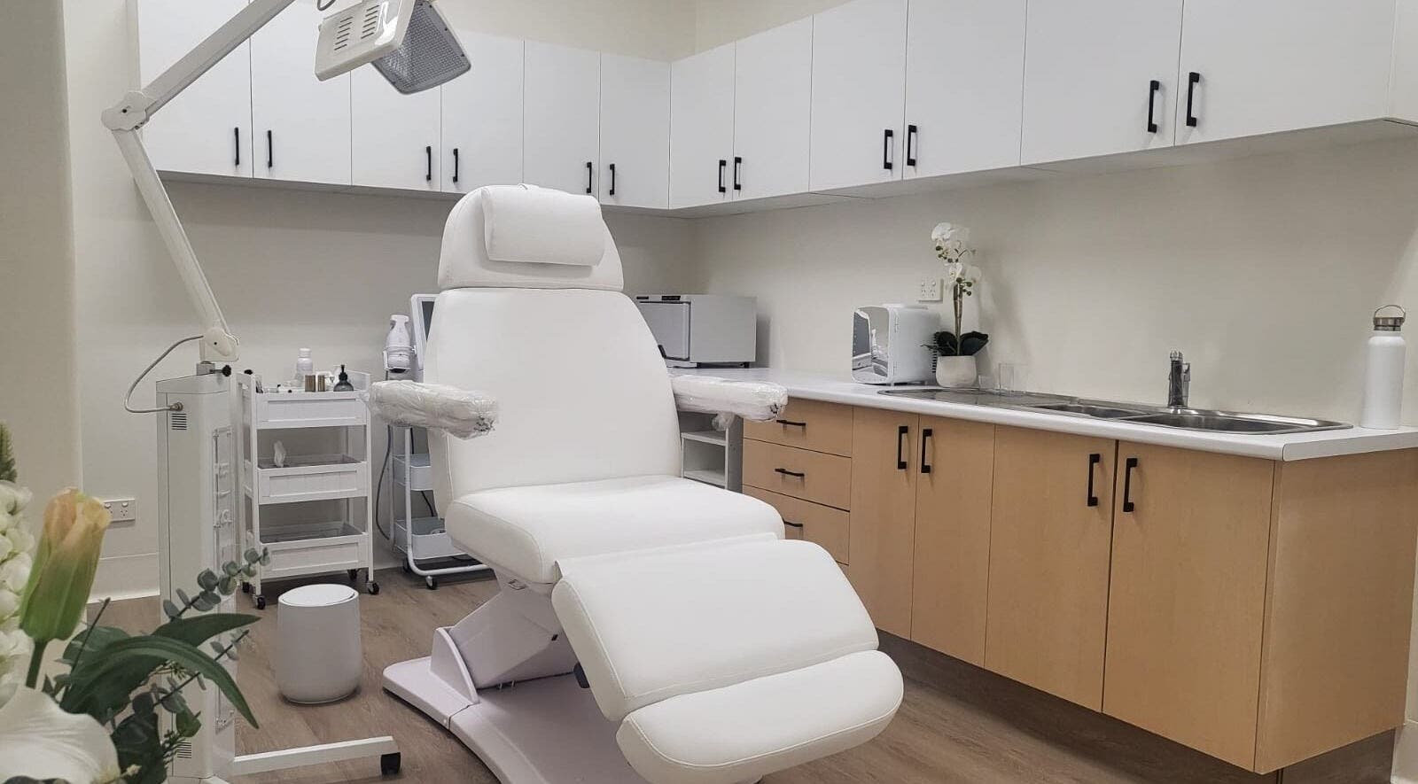 Modern treatment room at Lumina Skincare Clinic, Gold Coast, Queensland, AU with white chair and cabinets.