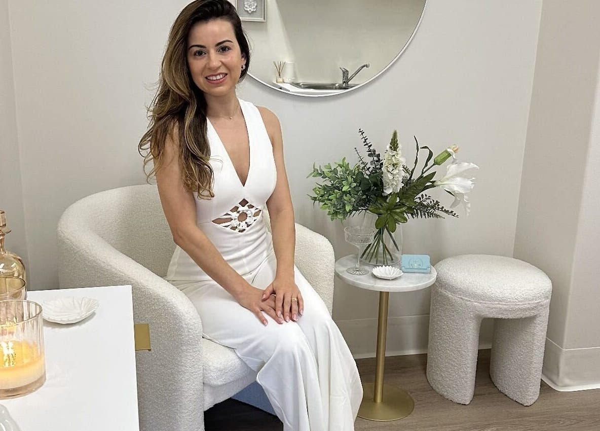 Woman seated in a chic, white chair at Lumina Skincare Clinic, Gold Coast, Queensland, AU.