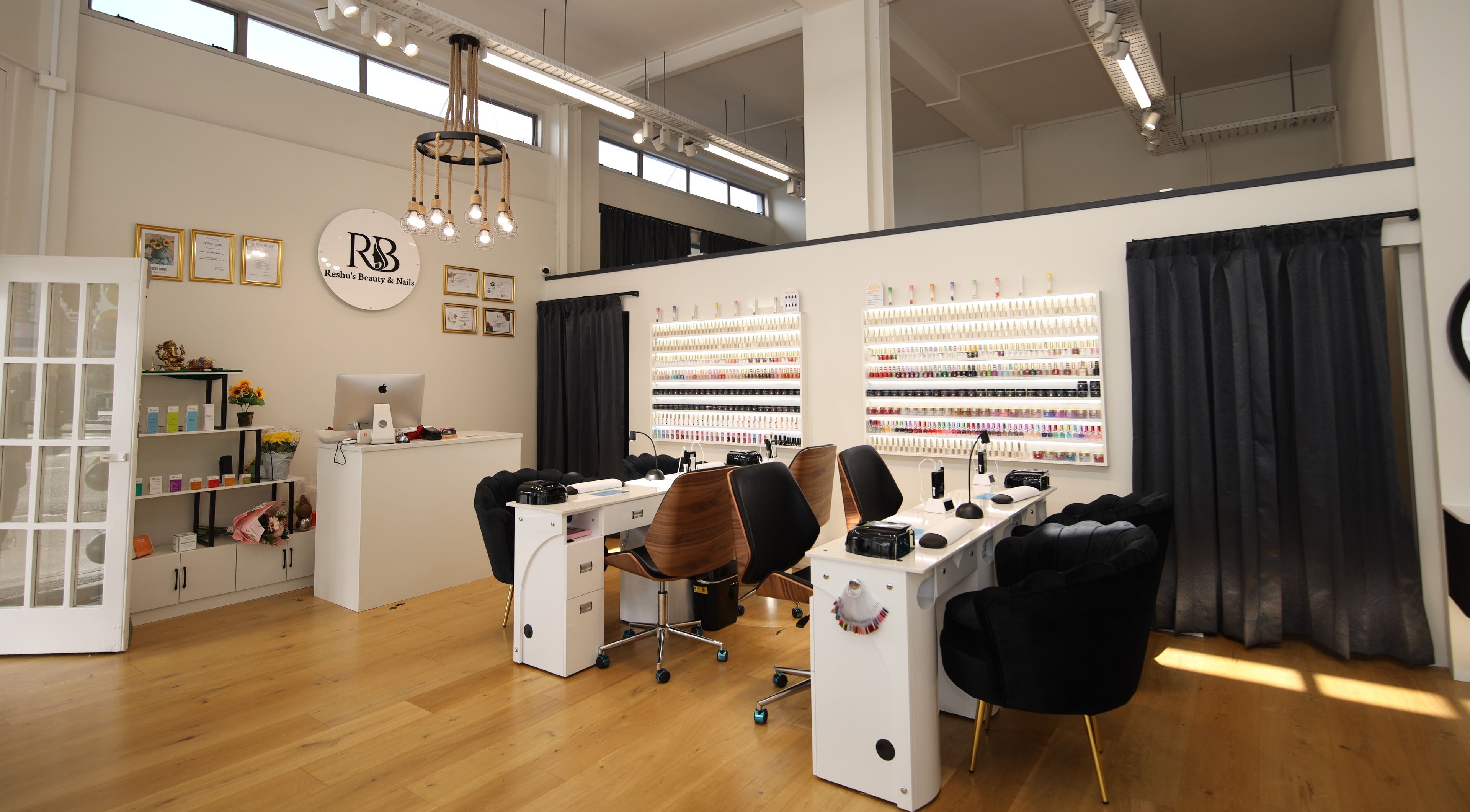 Chic interior of Reshu's Beauty & Nails PONSONBY in Auckland, NZ showing manicure stations and elegant decor.