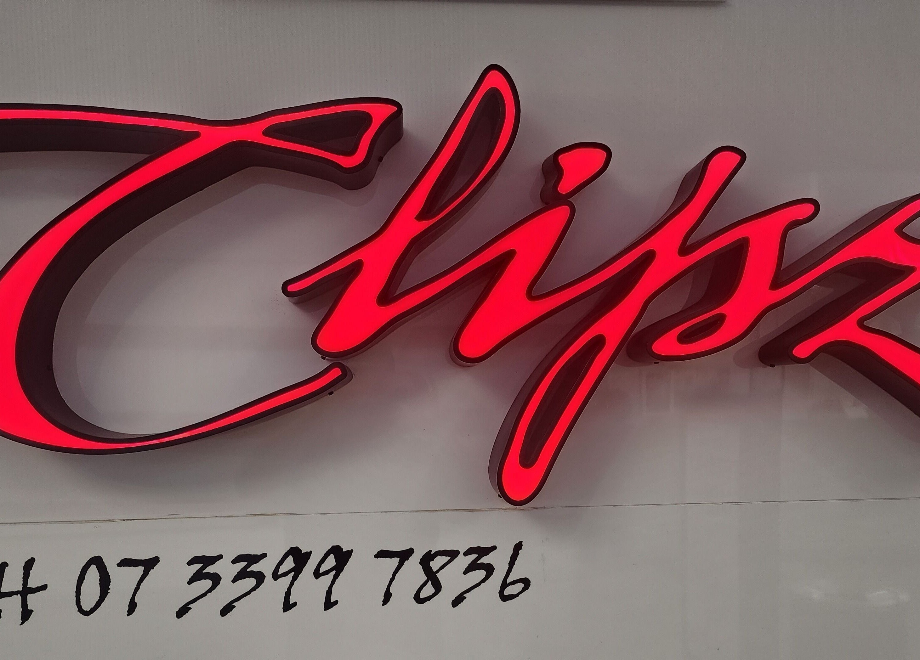 Illuminated sign of Clipz Hair Design in Morningside, QLD, AU, highlighting vibrant red letters against a sleek background.