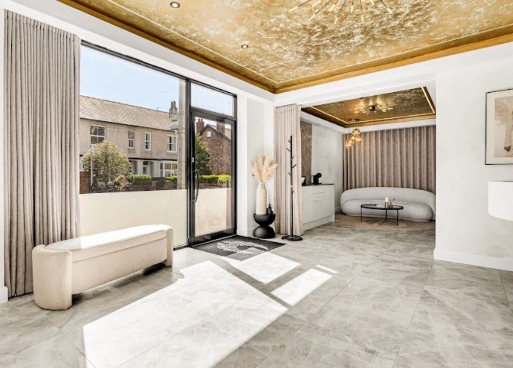 Luxurious bright lounge at Suburban Glow, Wilmslow, England, GB with gold ceiling and large windows.