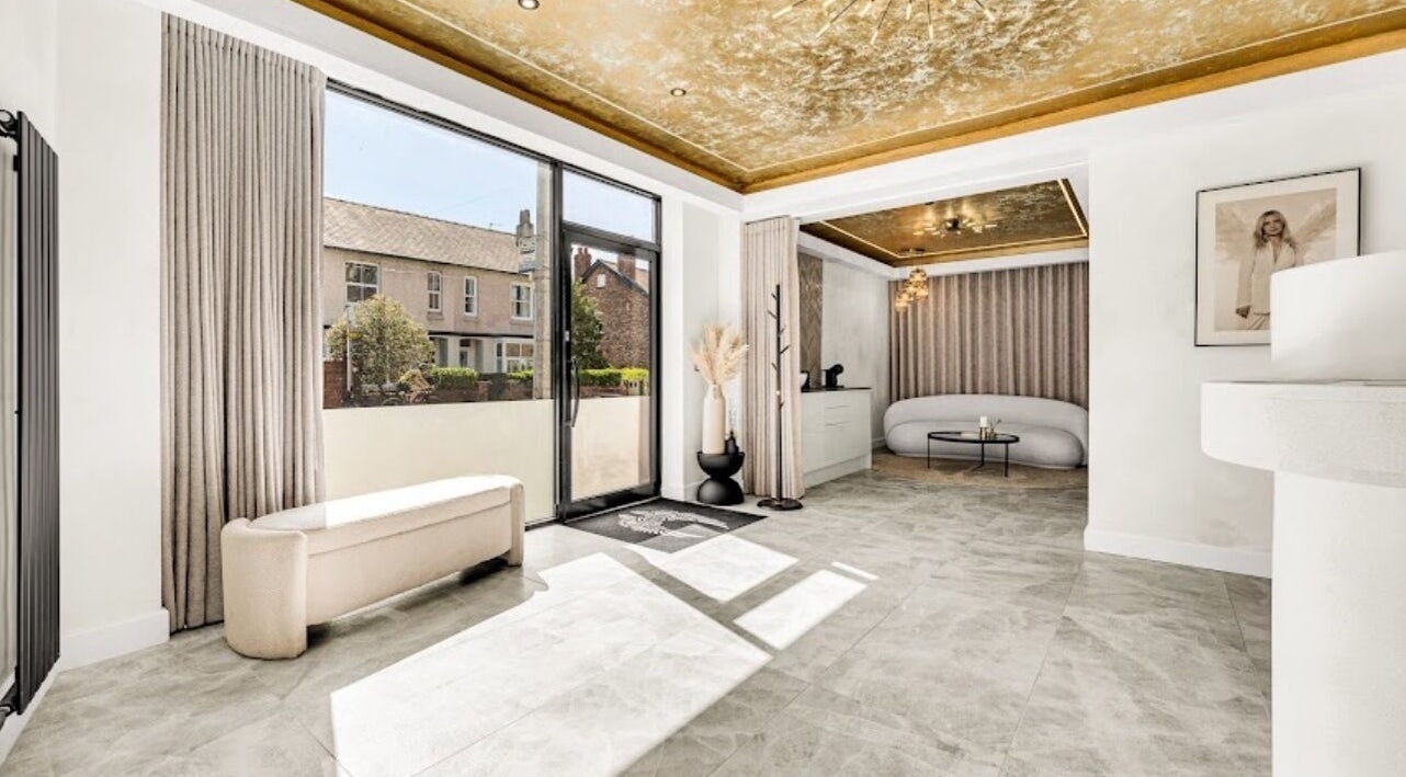 Luxurious bright lounge at Suburban Glow, Wilmslow, England, GB with gold ceiling and large windows.