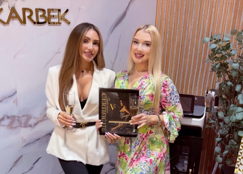 Two women holding a certificate and champagne at PMU Salon VS, Dallas, Texas, US.