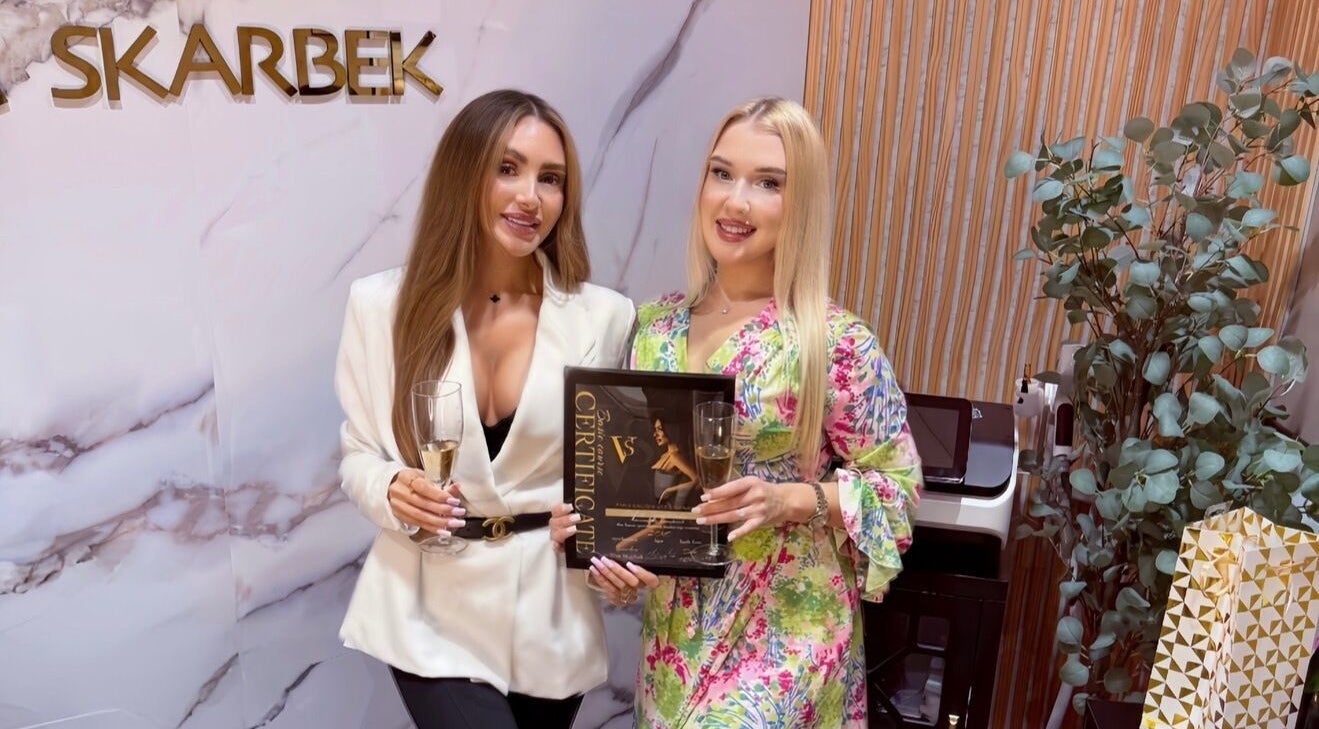 Two women holding a certificate and champagne at PMU Salon VS, Dallas, Texas, US.
