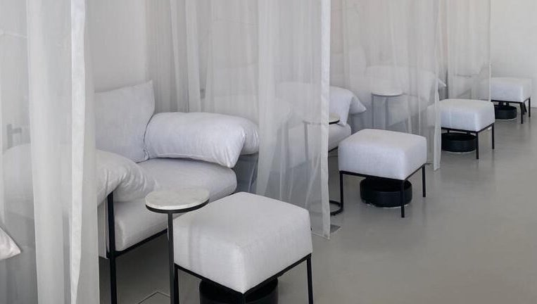 Relaxing spa lounge at De Oliva Spa, Riyadh, SA, featuring cozy white seating and translucent curtains.