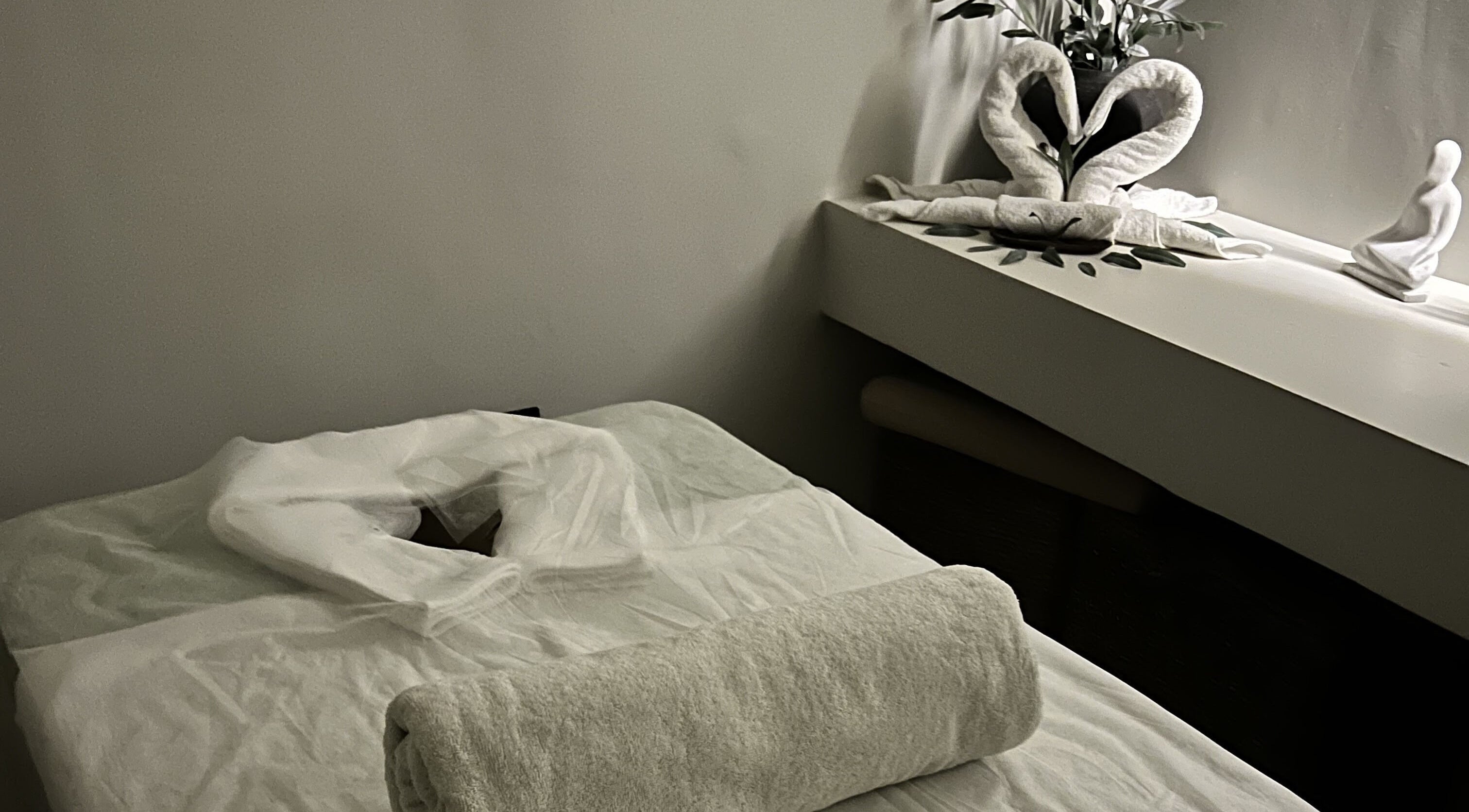 Cozy massage room at De Oliva Spa, Riyadh, SA with neatly folded towels and calming decor.