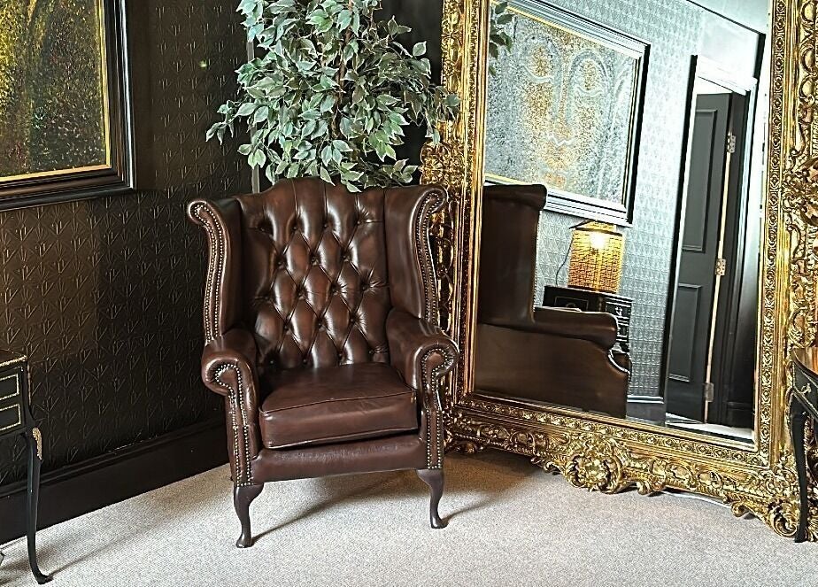 Elegant lounge with a leather chair and ornate mirror at The Mansion Spa, Birmingham, England, GB.