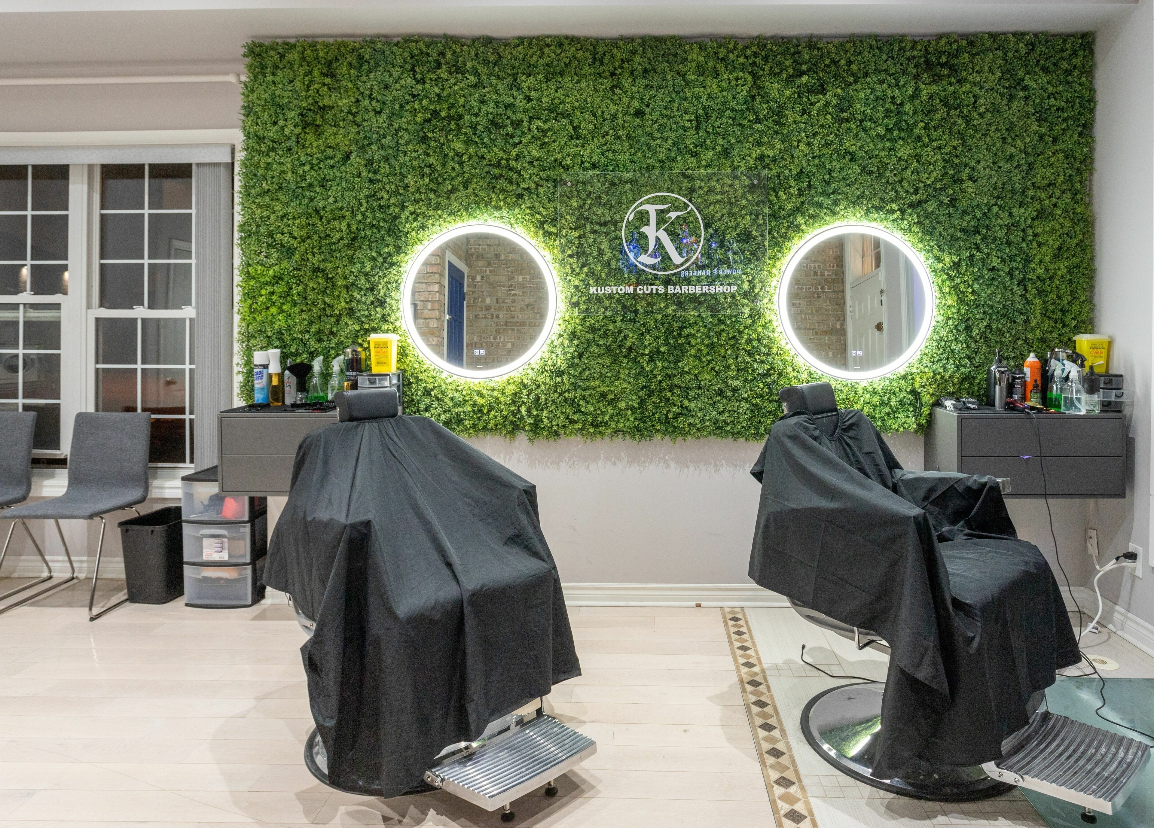 KustomCuts barbershop in Toronto, Ontario, CA features greenery wall and modern styling chairs.