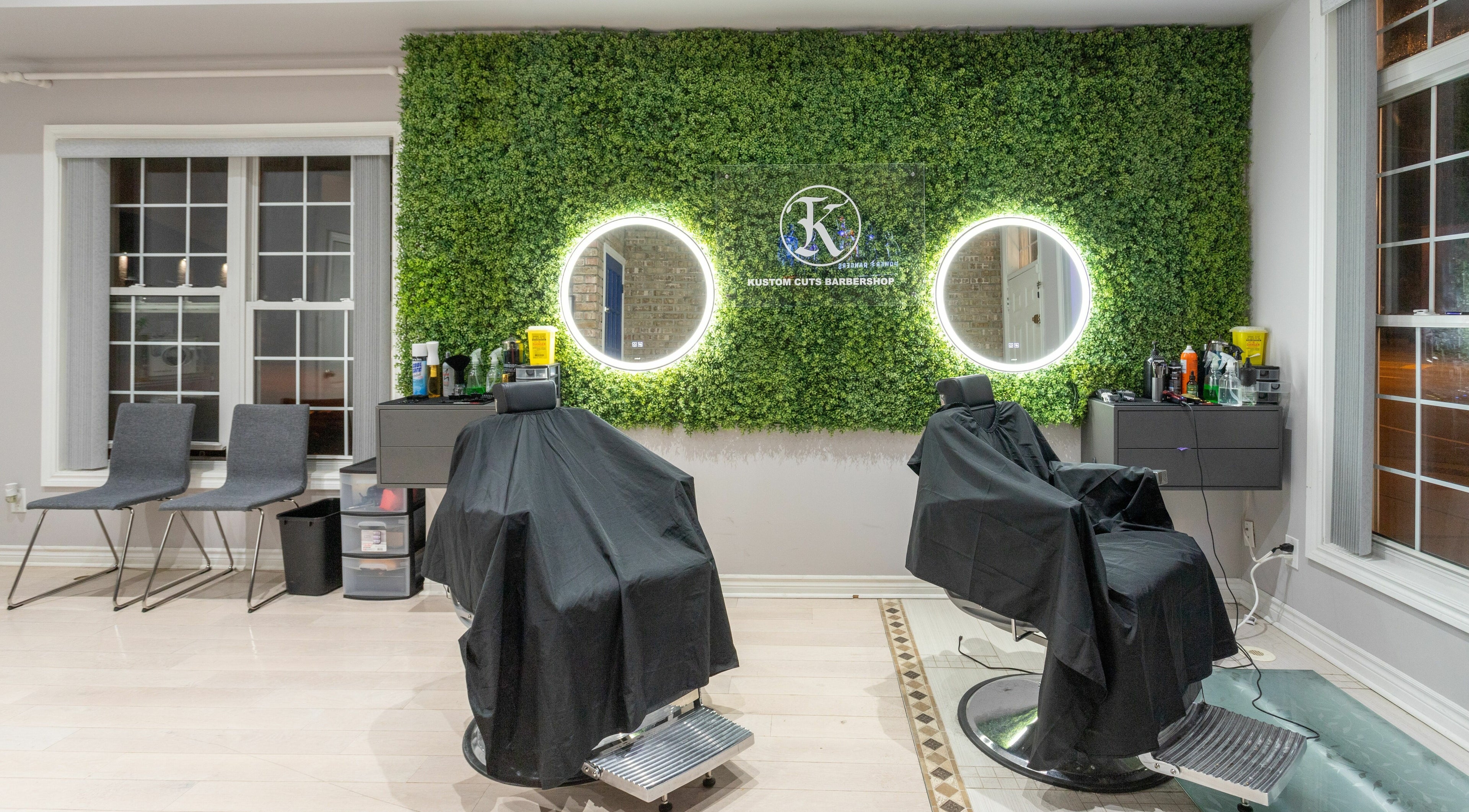 KustomCuts barbershop in Toronto, Ontario, CA features greenery wall and modern styling chairs.