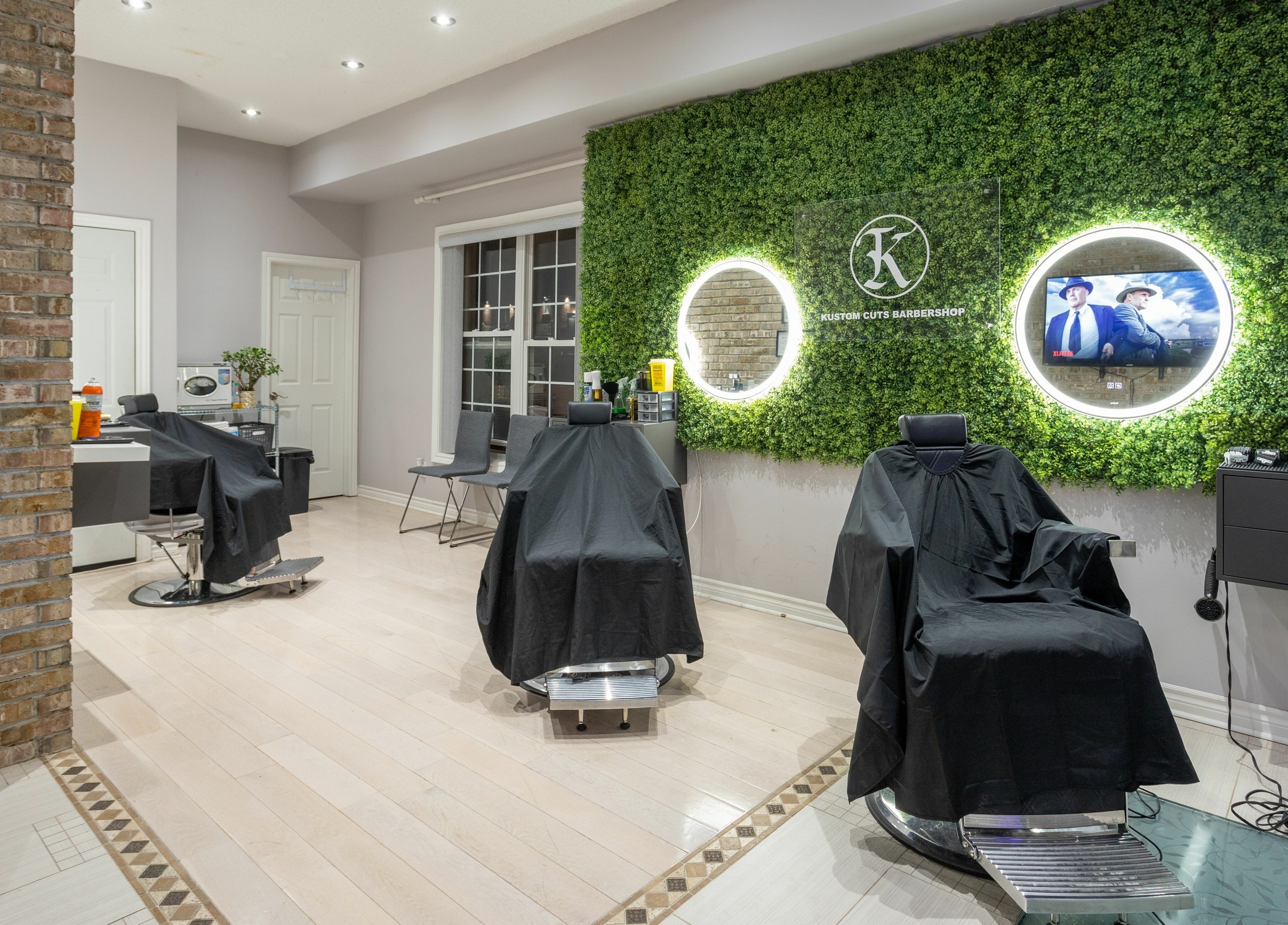 Modern barbershop at KustomCuts, Toronto, Ontario, CA with chic decor and lush greenery wall.