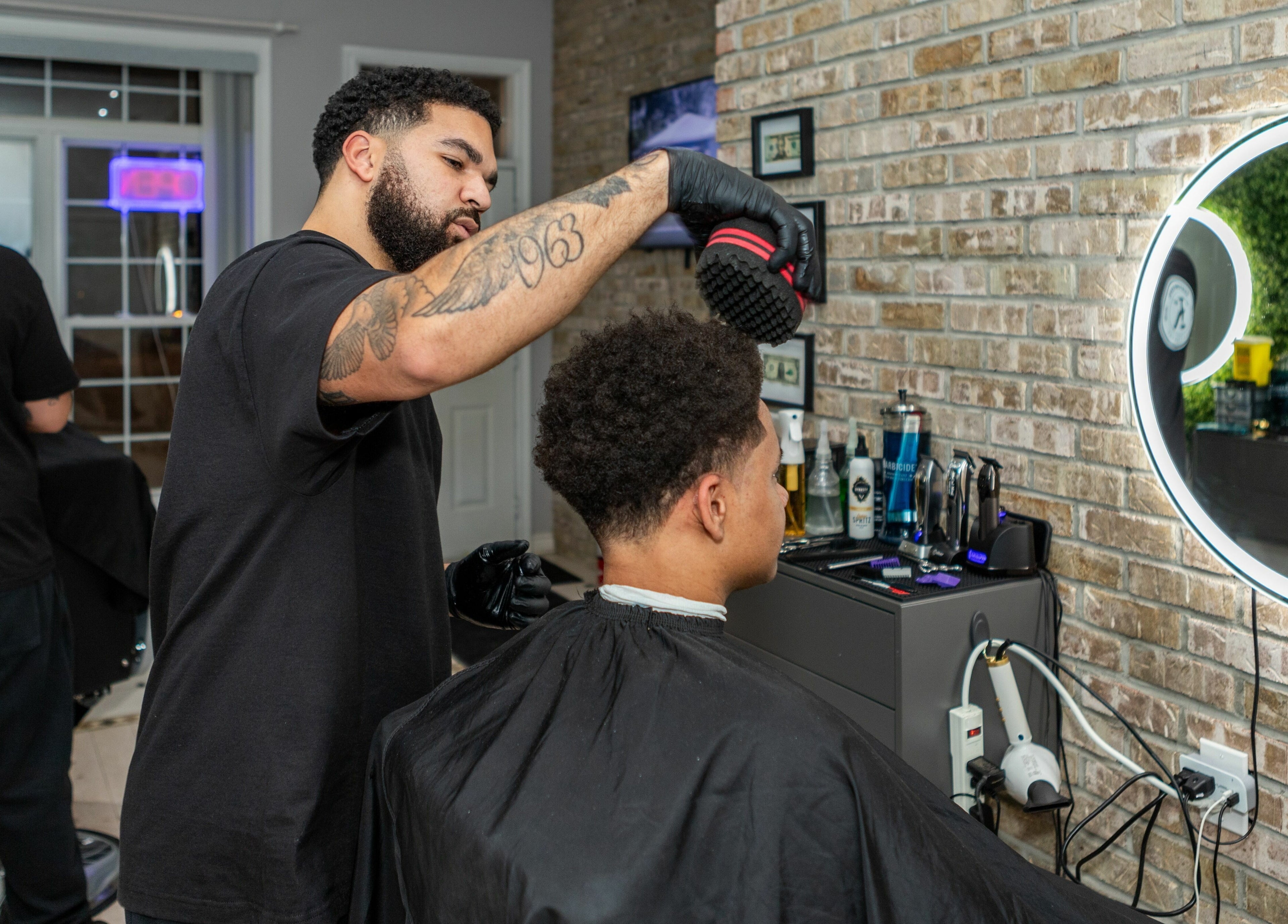 Barber expertly styles hair at KustomCuts in Toronto, Ontario, CA. Modern grooming in vibrant setting.