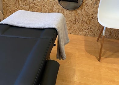 Sala de terapia em Studio Bruna Beauty, Parede-Cascais, Lisboa, PT, com cama preta e cadeira branca.