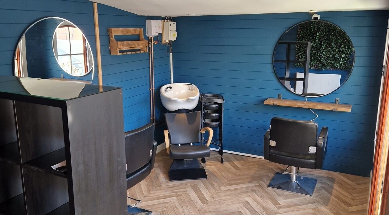 Cozy salon corner at The Hair Shed, Basildon, England with blue walls and styling chairs.