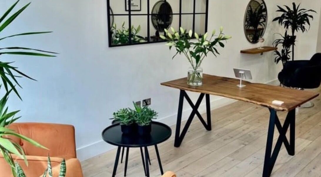 Stylish plant-decorated area at Bloss Hair, Keynsham, England, GB, featuring a wooden table and modern decor.