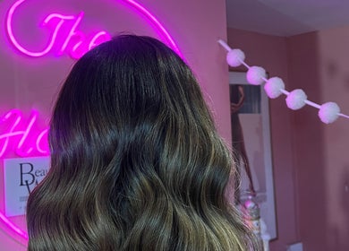Stylish wavy hairstyle at JessicaLibbyHair, Hinckley, England. Neon sign enhances the elegant salon experience.