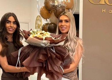 Two stylists at JessicaLibbyHair Hinckley, England, GB, holding a bouquet and smiling amid decor.