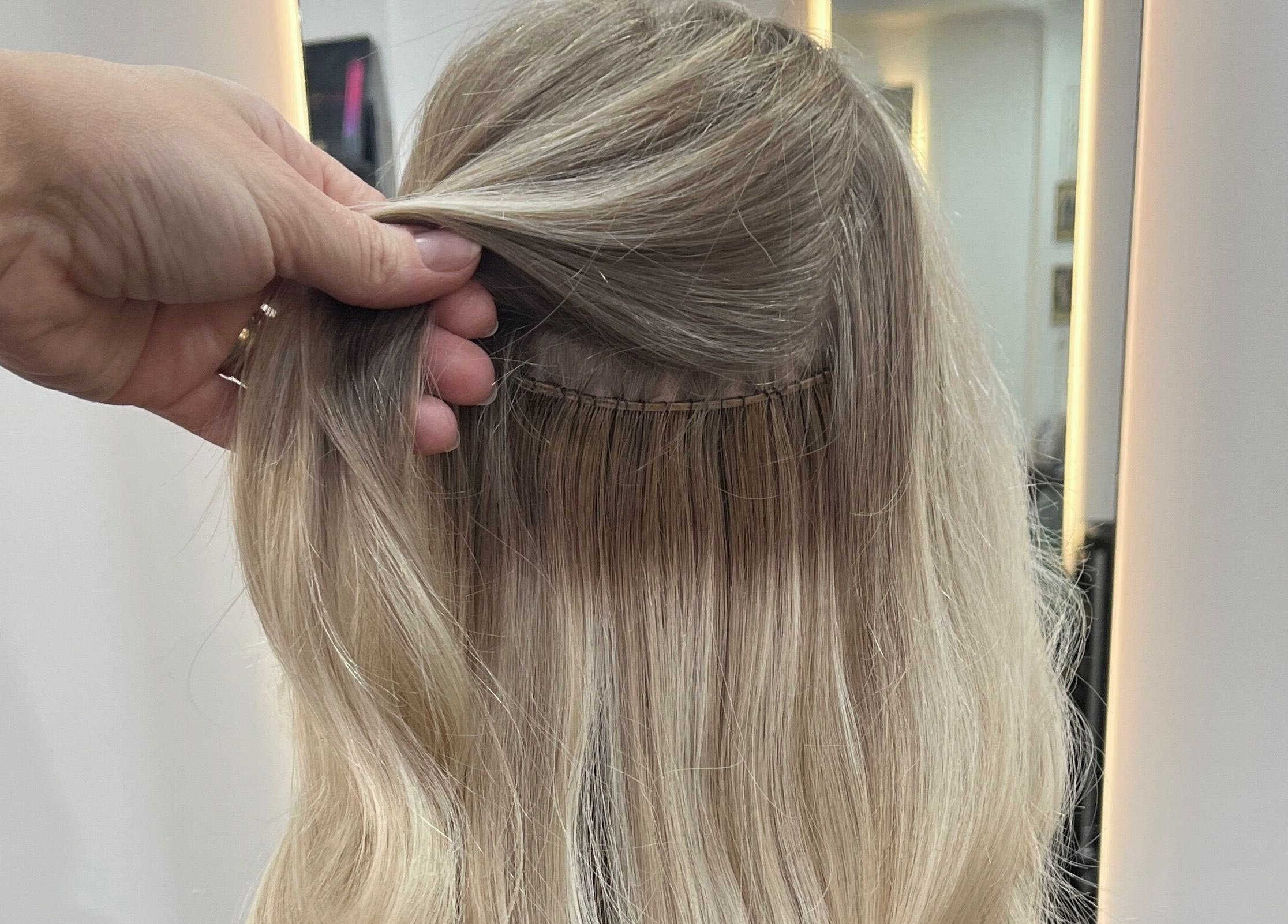 Hair extension detail at Aura Extensions, Twickenham, England, GB. Close-up of installation in salon setting.