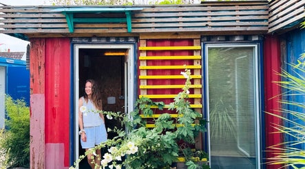 Bright, colorful entrance of Lucy Massages You in Margate, GB, featuring vibrant flowers and rustic wood accents.