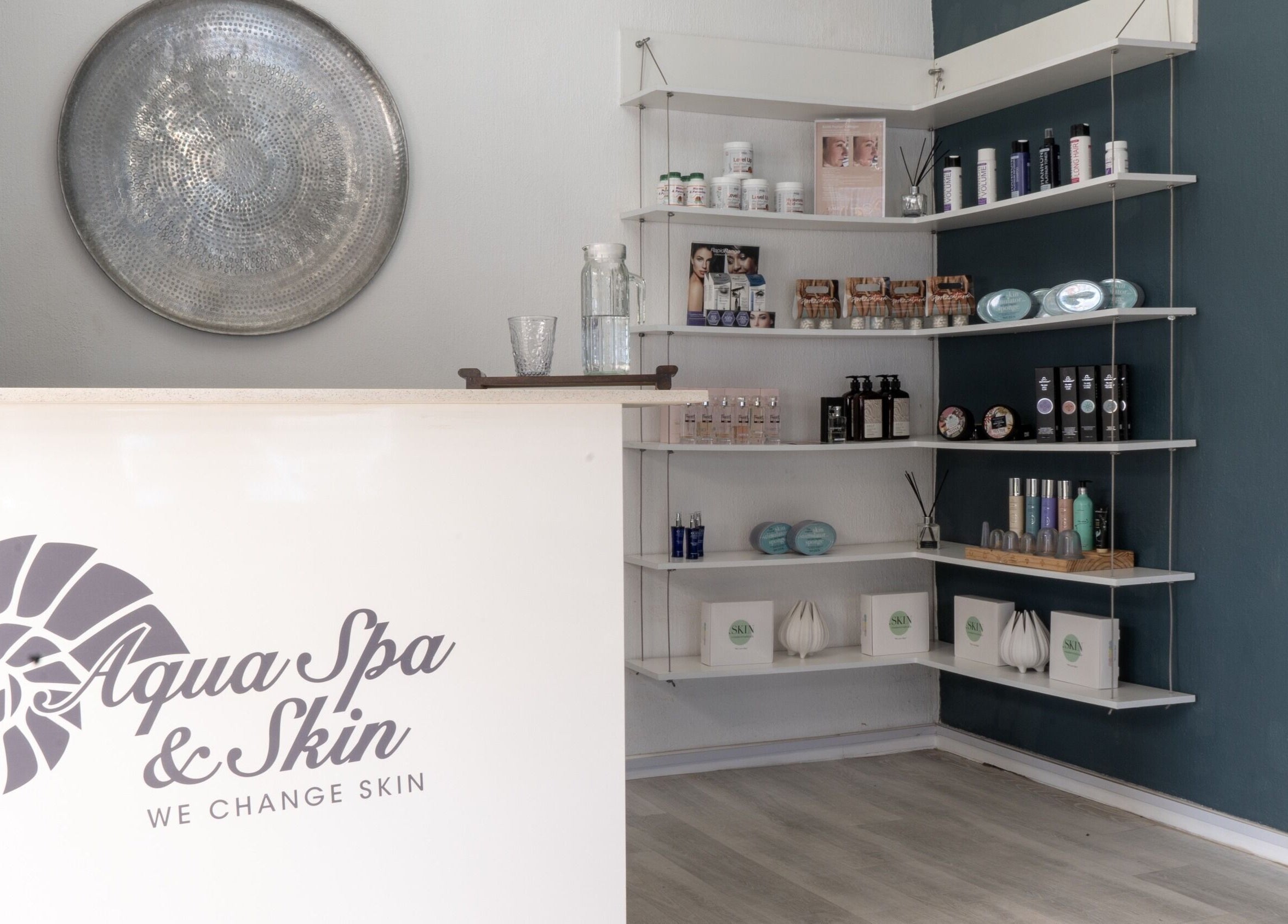 Reception area at Aqua Spa & Skin, Surf Village, Jeffreys Bay with shelves showcasing beauty products.