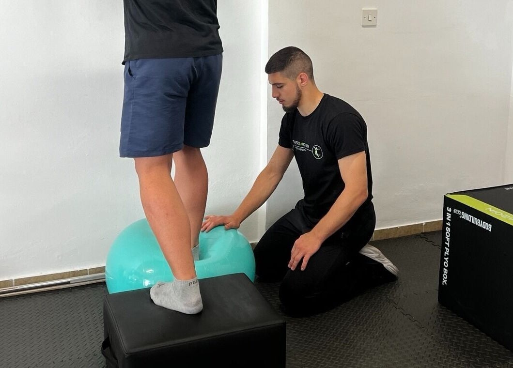 Therapist assists balance exercise at Theramotion Physiotherapy, Λευκωσία, Λευκωσία, CY for strength training.