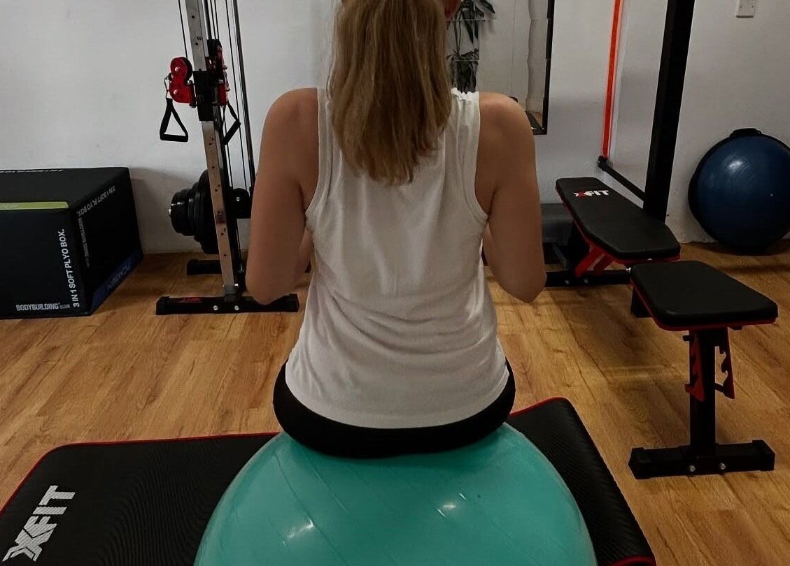 Woman using fitness ball at Theramotion Physiotherapy, Λευκωσία, CY for core strength exercises.