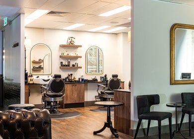 Modern interior of True Cut Barber Studio in Sydney, New South Wales, AU, featuring stylish chairs and mirrors.
