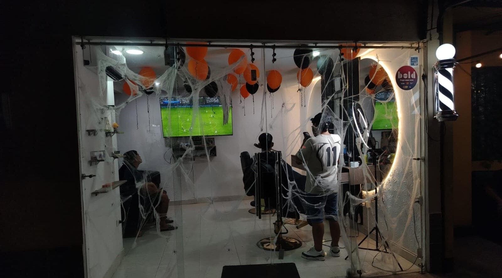 Interior decorado de JR STUDIO BARBER en Granada, Meta, CO, con globos y telarañas.