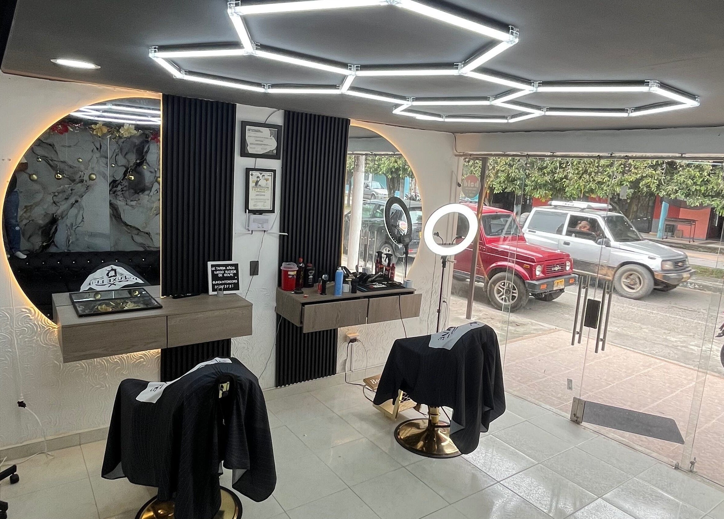 Interior moderno de JR STUDIO BARBER en Granada, Meta, CO con espejos iluminados y sillas de peluquería.