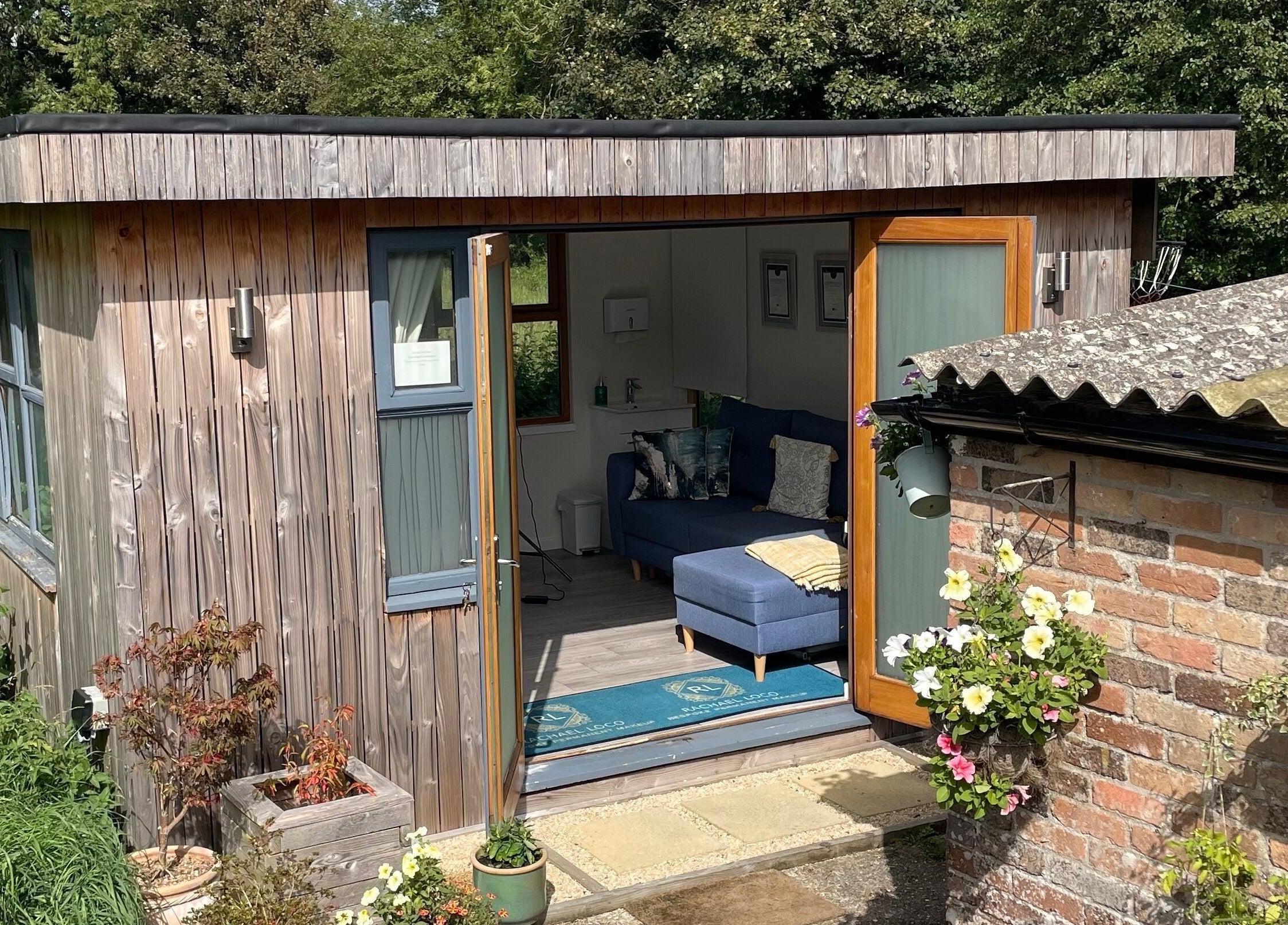 Charming cabin at Rachael Loco Permanent Makeup, Dorchester, England, GB, with open doors and vibrant flowers.