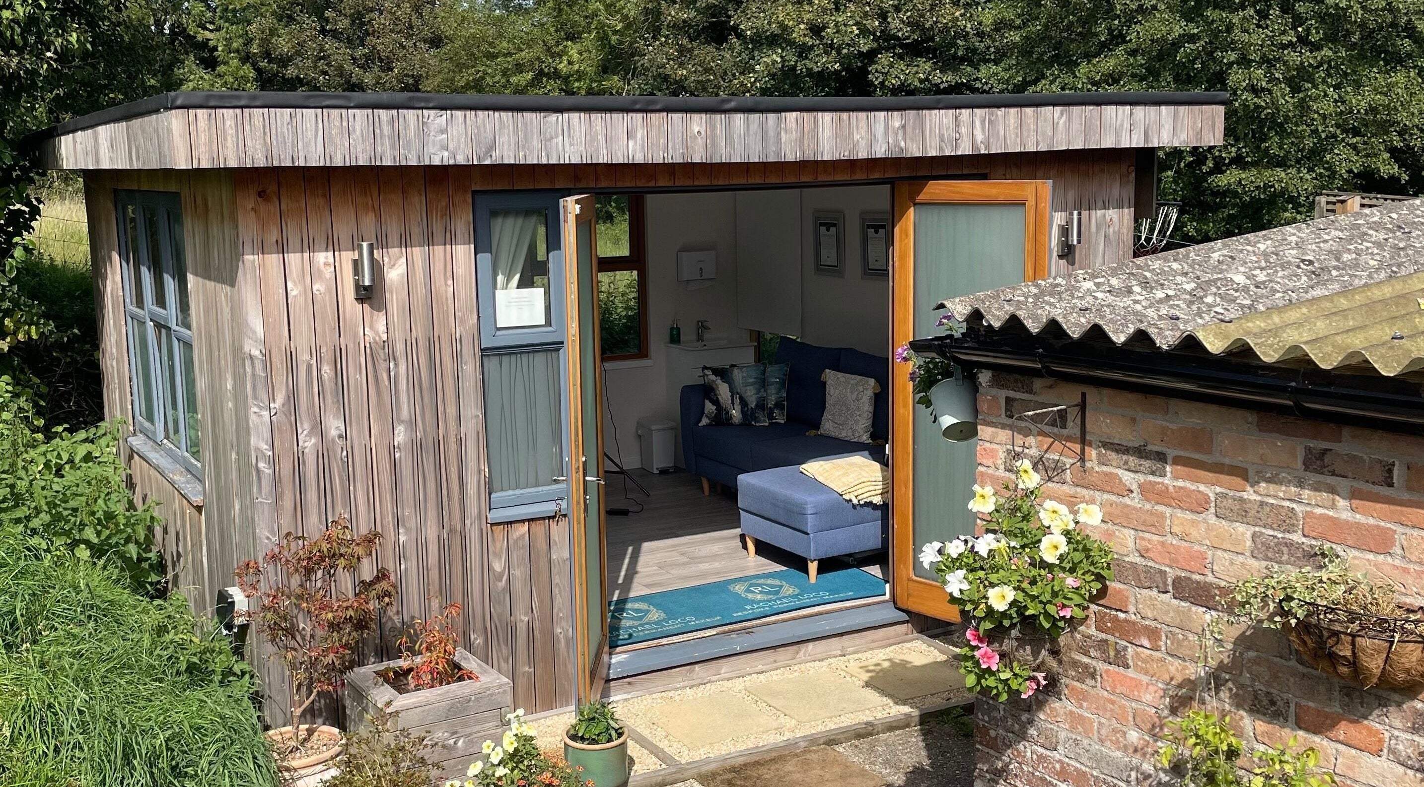 Charming cabin at Rachael Loco Permanent Makeup, Dorchester, England, GB, with open doors and vibrant flowers.