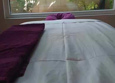 Κρεβάτι μασάζ με μωβ πετσέτα στο Euphoria Aura, Limassol, CY.
