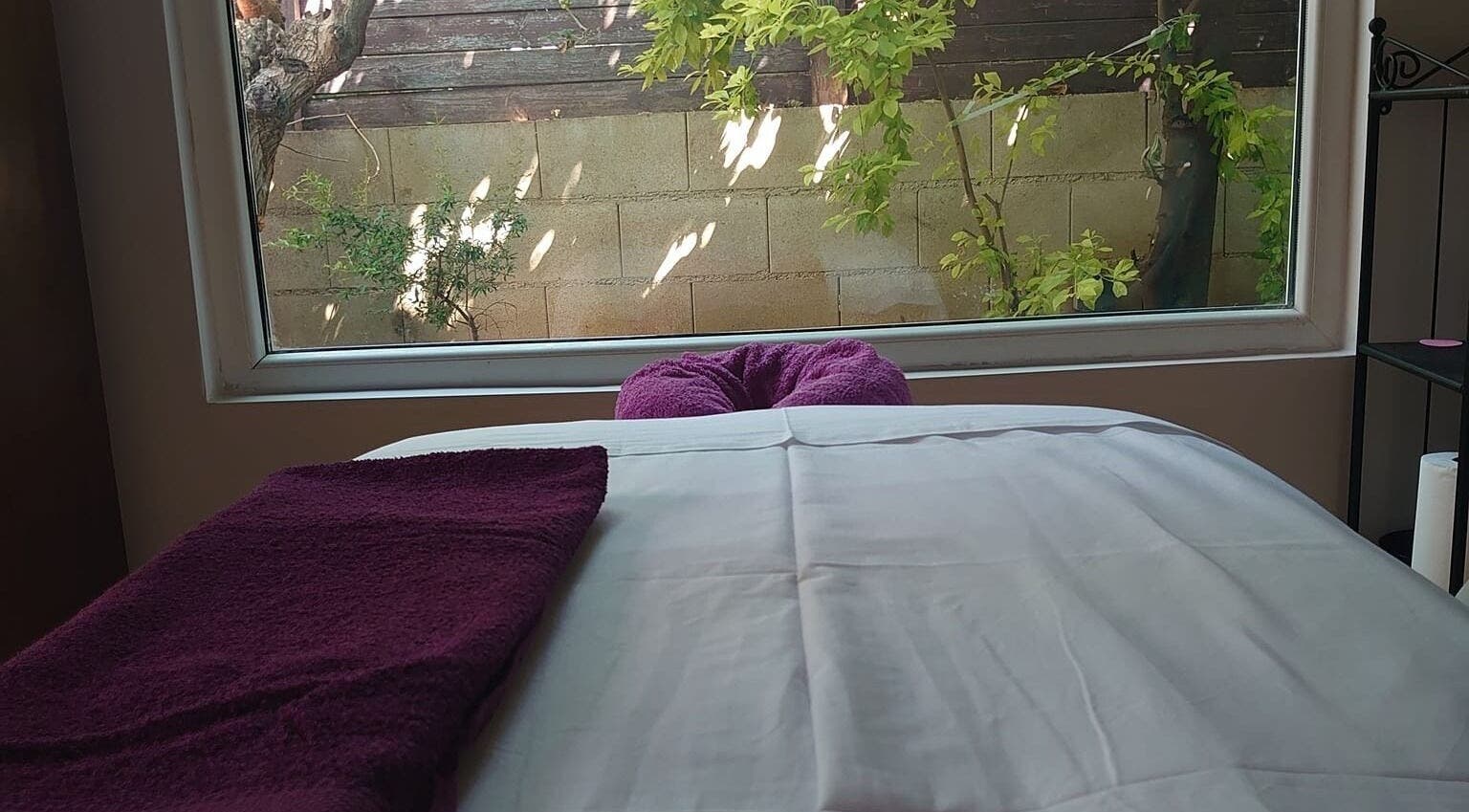 Δωμάτιο μασάζ στο Euphoria Aura, Λεμεσός, CY, με θέα σε πράσινο τοπίο από το παράθυρο.