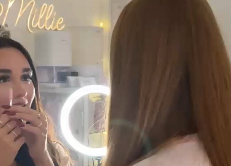 A woman looks into a lighted mirror at Pretty by Millie, Bewdley, England, GB, preparing for a beauty treatment.