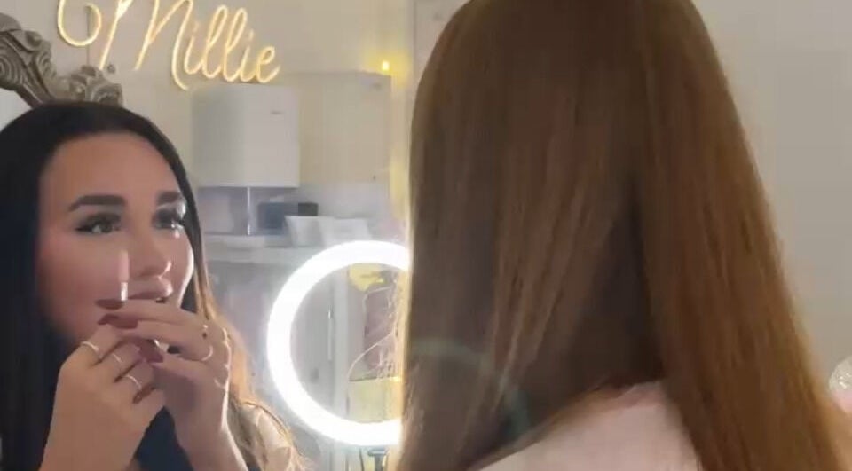 A woman looks into a lighted mirror at Pretty by Millie, Bewdley, England, GB, preparing for a beauty treatment.