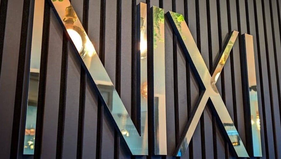 Glossy NIXI Lounge sign on textured wall at Ammanford, Wales, GB, reflecting ambient light.