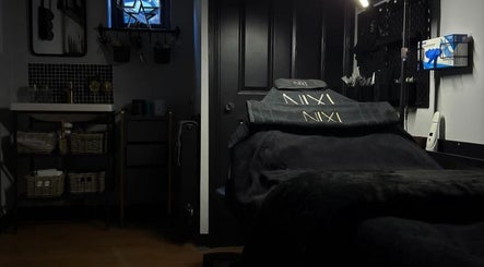 Cozy treatment room at NIXI Lounge, Ammanford, Wales, GB, featuring elegant black decor and a comfortable treatment bed.