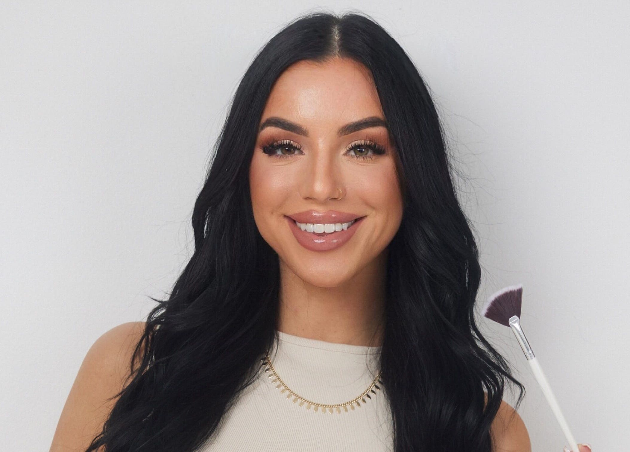 Smiling woman holding makeup brush at Balanced Beauty Med Spa, Vaughan, Ontario, CA.