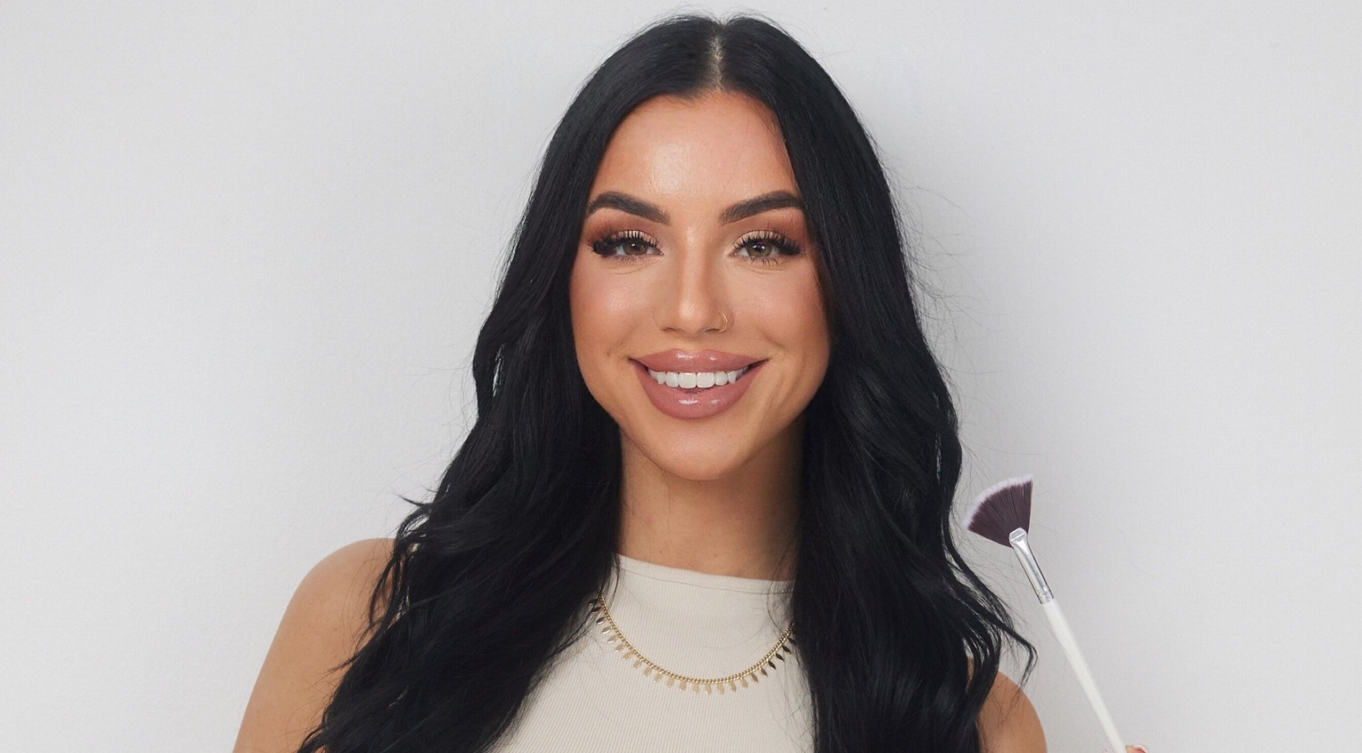 Smiling woman holding makeup brush at Balanced Beauty Med Spa, Vaughan, Ontario, CA.